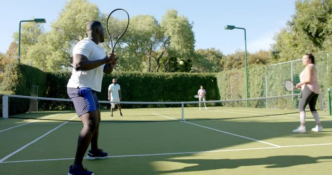 Playing doubles tennis, Diverse Friends enjoying match on outdoor court, having fun