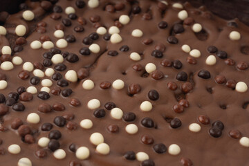 Chocolate brownie cake texture background sprinkled with white and dark balls, brounie banner