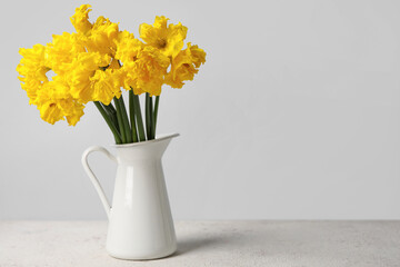 Vase with narcissus flowers on table near grey wall