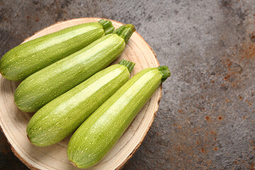 Board with fresh green zucchini on dark background