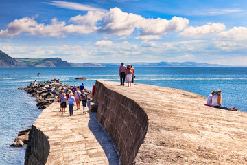 Lyme Regis, Dorset, England, UK - Visitors enjoying the good weather on The Cobb.
