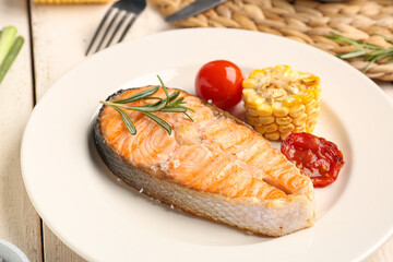 Plate with tasty grilled salmon steak on light wooden background