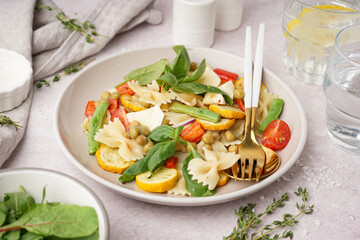 Plate of tasty pasta salad with peas and basil on white background