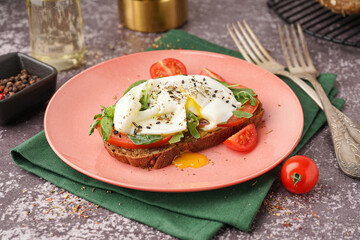 Plate of tasty sandwich with egg on grey background