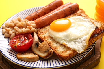Plate of tasty English breakfast with fried egg on yellow background