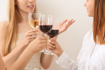 Women with glasses of exquisite red wine on light background