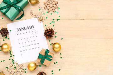 Paper calendar for January with gift boxes and Christmas decorations on wooden background