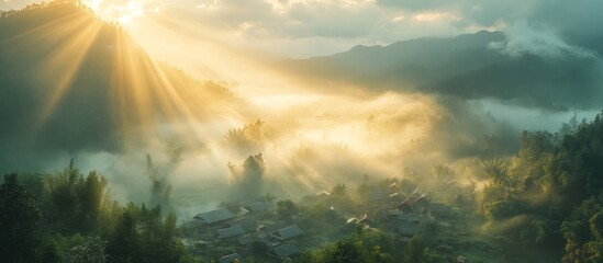 Fototapeta premium Sunrise rays over misty mountain village