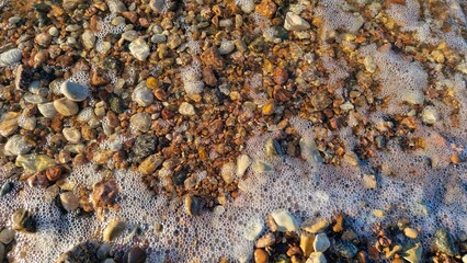 Foamy Seawater Mixing with Beach Pebbles at Dusk