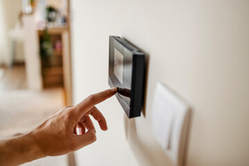 Close up of finger pressing temperature regulator in house.