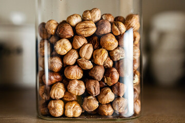 Close up of hazelnuts in jar on table.