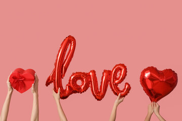 Women with word LOVE made of balloons and gift on pink background. Valentine's Day celebration