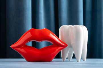 Ceramic vase in the form of red lips and a white human tooth on a background of blue velvet curtains