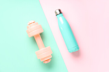 Dumbbell and bottle of water on color background