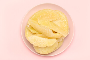 Plate with pomelo fruit pieces on pink background
