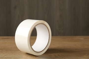Roll of masking tape on wooden table, closeup. Space for text