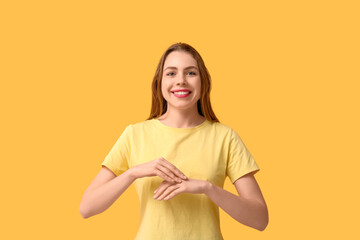 Obraz premium Young deaf mute woman using sign language on orange background