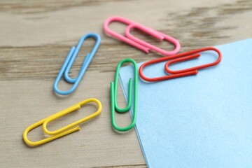Many colorful clips and paper notes on wooden table, closeup
