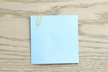 Paper notes with clip on wooden table, top view. Space for text