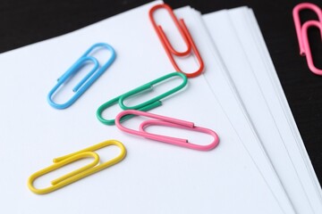 Many colorful clips and paper notes on black wooden table, closeup
