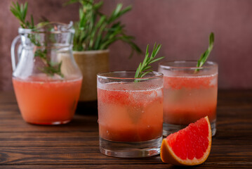 Grapefruit and peach lemonade with rosemary, ice and a slice of grapefruit on brown background. Healthy drink, sugar and alcohol free.