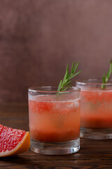 Grapefruit drink lemonade with rosemary and peach in a glasses and a slice of grapefruit on a wooden table. Healthy drink, sugar and alcohol free. Vertical orientation.