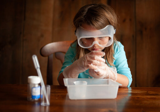 Young girl wearing goggles doing science experiment at home