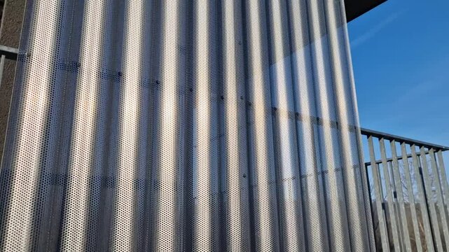 building is lined with square panels. metal sheet wall cladding with scalloped design. corrugated sheet, dark gray, riveted. horizontal stripes, shadows, corner, fence, aluminium, sheet, hotel
terrace