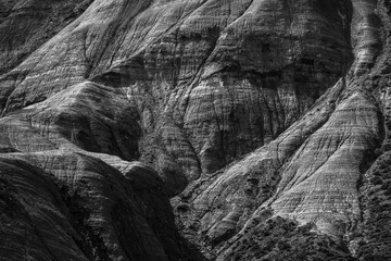 Monochromatic depiction showcasing intricate textures and patterns of natural rock formations in a rugged landscape.