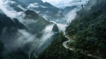 Obraz premium Winding Mountain Road Through Misty Green Valley
