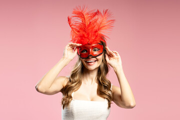 Smiling woman wearing red carnival mask with feathers