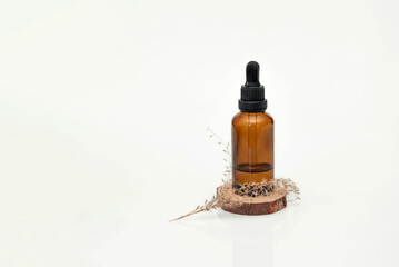 Amber dropper bottle with essential oil or serum on wood slice and dried flowers on white background,Natural skincare and beauty products