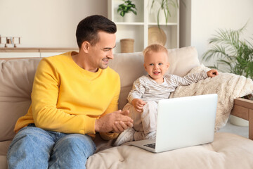 Father sitting on sofa and showing something to his son at home