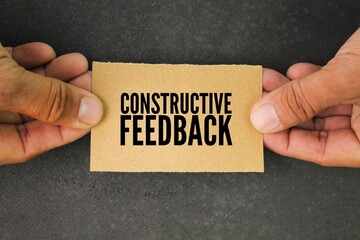 hand and paper with the word constructive feedback. the concept of consumer or customer response. a...