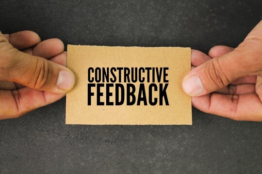 hand and paper with the word constructive feedback. the concept of consumer or customer response. a response to someone's activity aimed at helping them become more effective