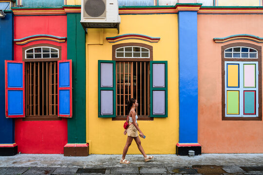 Young asian woman walking near colorful house, Little India quarter, Singapore