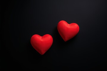 two red hearts are placed on a black surface
