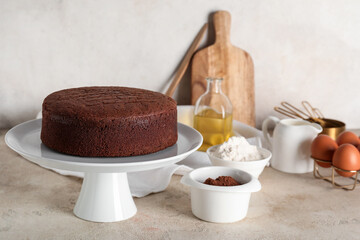Tasty chocolate sponge cake with cocoa powder, eggs and flour on light grunge background