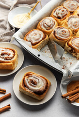 Freshly baked cinnamon rolls with cream cheese frosting and cinnamon sticks