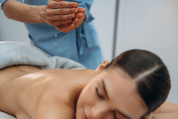Obraz premium Relaxed young woman getting massage by therapist in spa salon