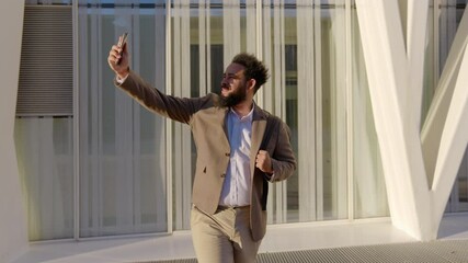 Successful businessman delights in his time spent outdoors as he takes a cheerful selfie using his smartphone. His stylish outfit reflects a perfect blend of professionalism and leisurely enjoyment