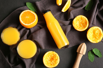 Bottle and glasses of fresh orange juice with mint on black background