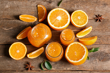 Jars of sweet orange jam with star anise and fruits on wooden background