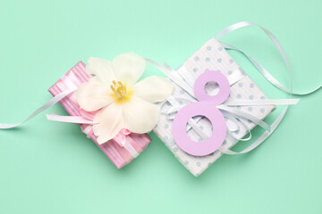 Figure 8 made of paper, flower and gift boxes on turquoise background. Women's Day celebration.