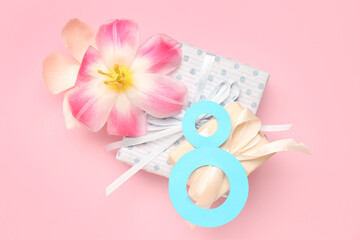 Figure 8 made of paper, flowers and gift boxes on pink background. Women's Day celebration.