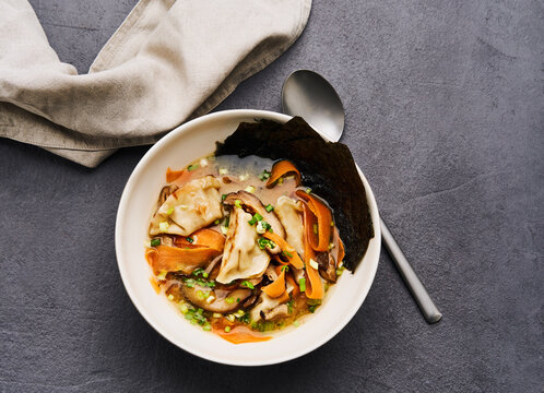 A comforting bowl of dumpling soup features tender dumplings, vibrant carrots, and green onions in a rich broth, creating a delightful meal perfect for any time