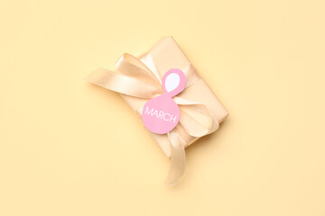 Composition with greeting card and gift box for Women's Day celebration on beige background