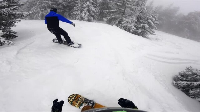 Snowboarder ride off-piste in the beautiful forest. Sportsman bypassing among the snowy fir trees.