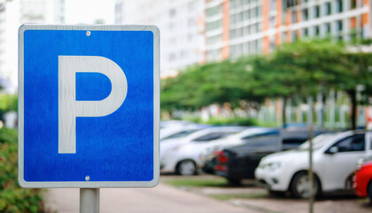Blue metal city street parking sign, blurred cars in background. Urban car park space, traffic