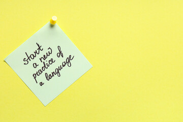 Green sticky note with text START A NEW PRACTICE OF A LANGUAGE on yellow background